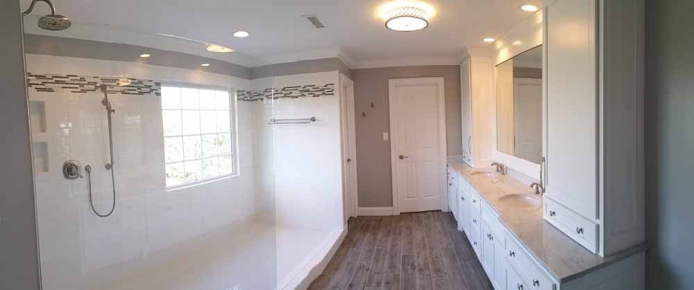 Wide bathroom with glass shower, white vanity and chrome fixtures