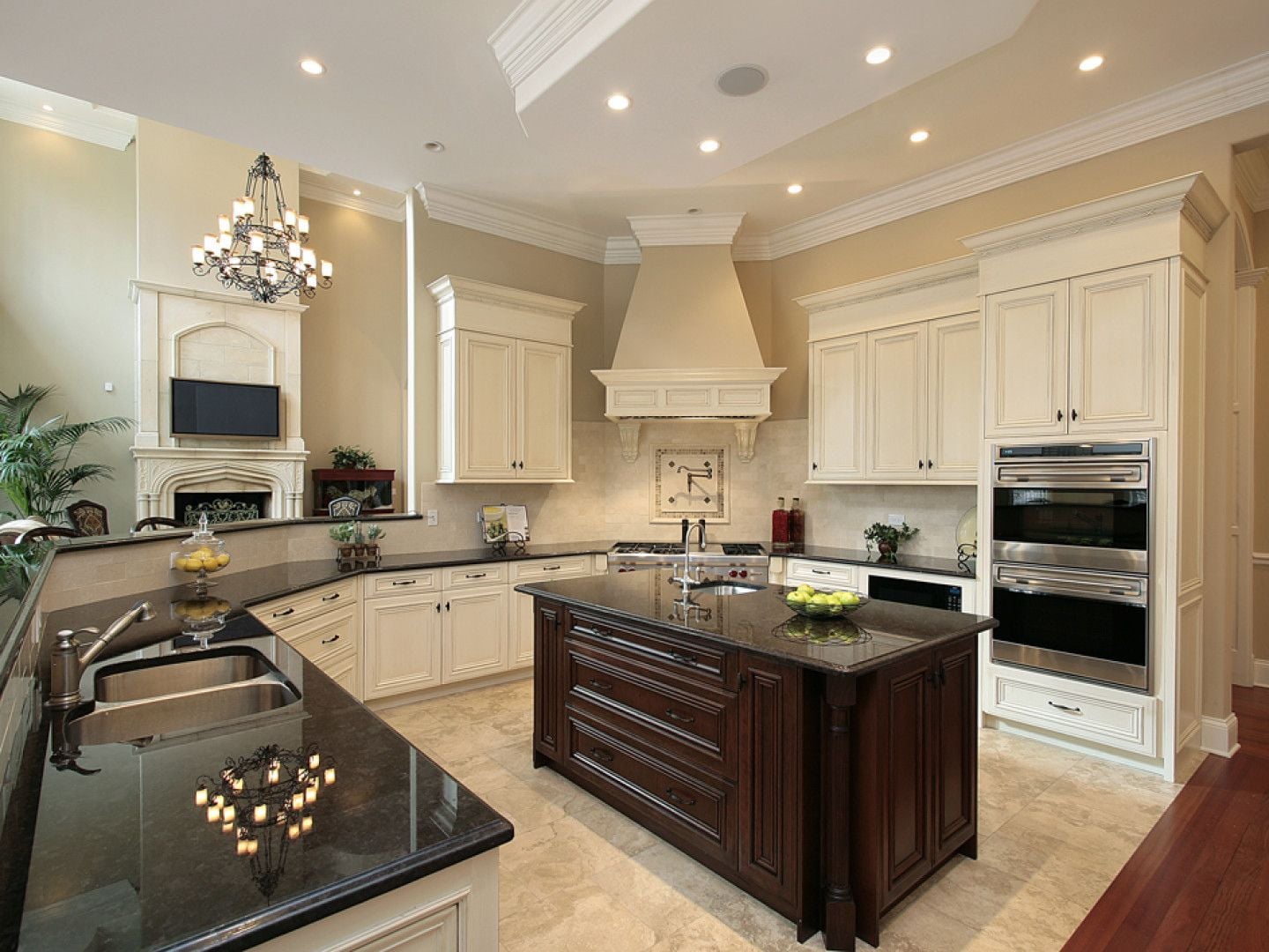 Traditional cream kitchen with a dark island, chandelier and wood floors