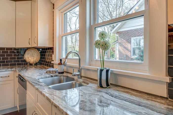 Kitchen sink and stone counter beneath a large window